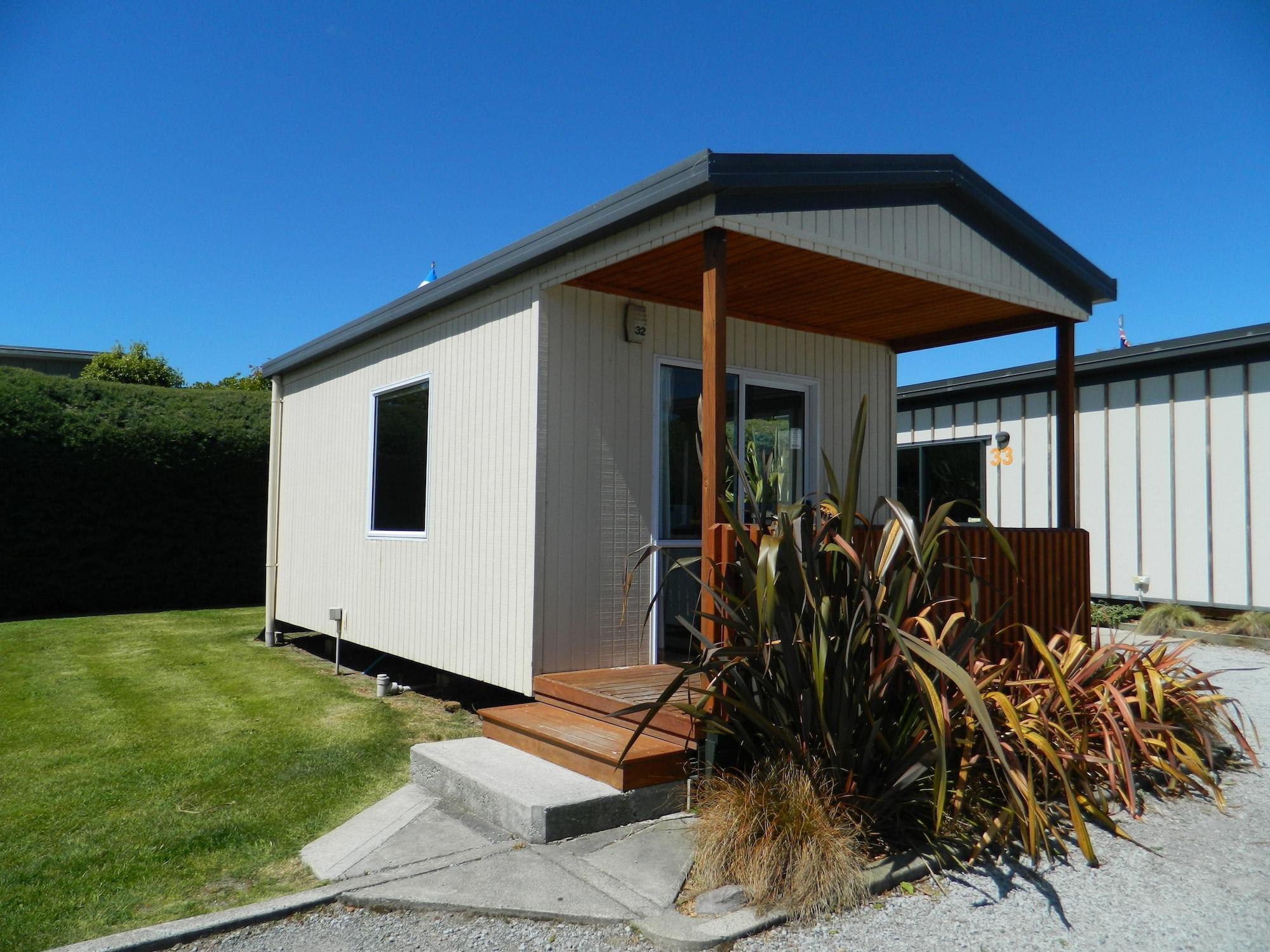 陶波德布雷思汽车旅馆酒店 外观 照片 The photo shows a small, modern cabin or vacation home. It features a light-colored exterior with a a small porch at the entrance. The porch has wooden steps that lead up to the front door. Surrounding the cabin is a neat lawn, with some landscaping 