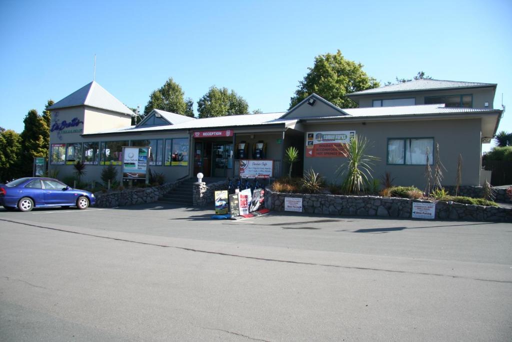 陶波德布雷思汽车旅馆酒店 外观 照片 The photo shows a building that appears to be a business or service center. It features a modern design with a peaked roof and a prominent entrance. The front is landscaped with some greenery, and there are signs displaying various services or busine