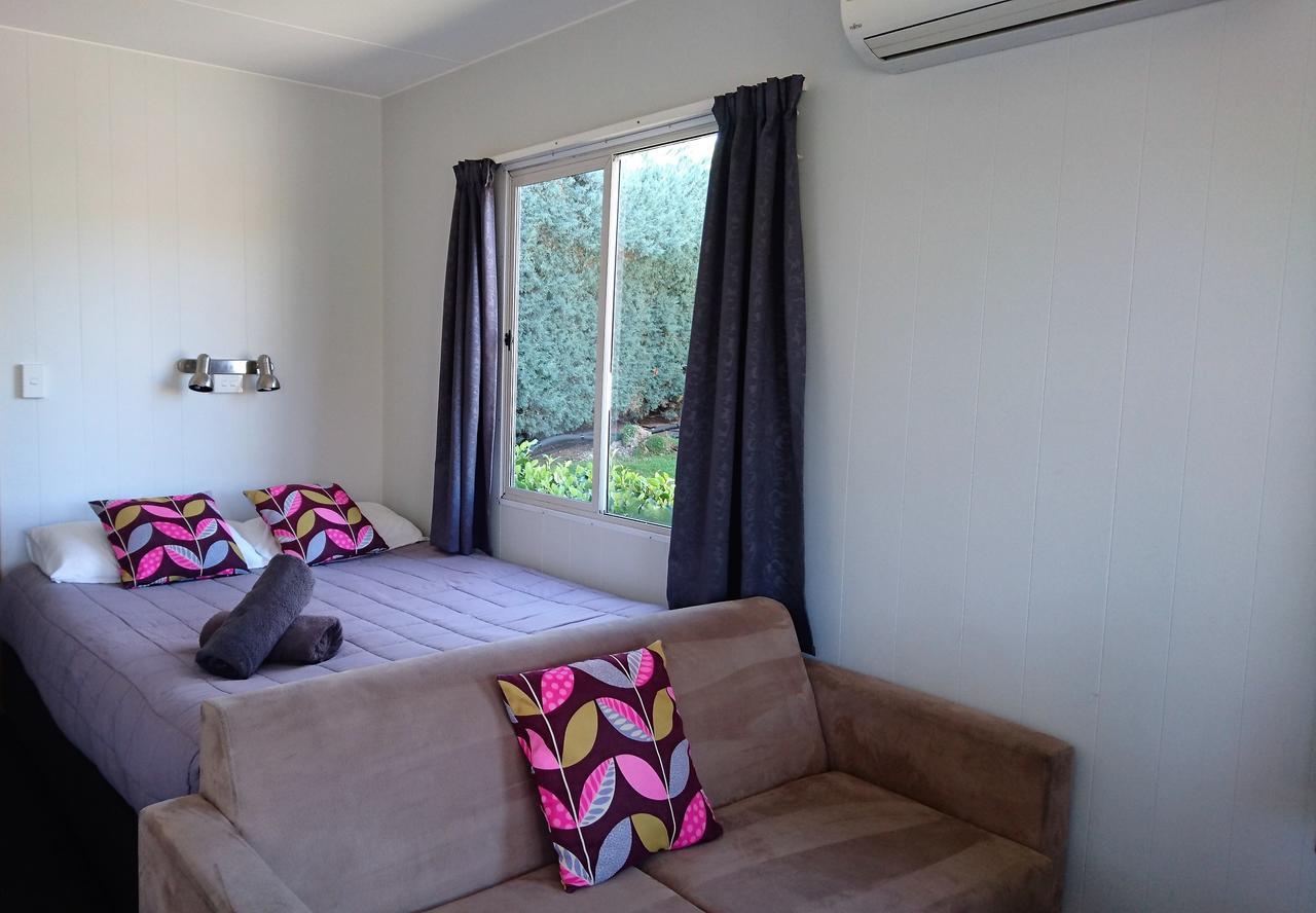 陶波德布雷思汽车旅馆酒店 外观 照片 The photo shows a cozy room featuring a bed with colorful patterned cushions and a brown sofa. There are two large windows with dark curtains, allowing natural light to brighten the space. The walls are painted in a light color, and there are some pl