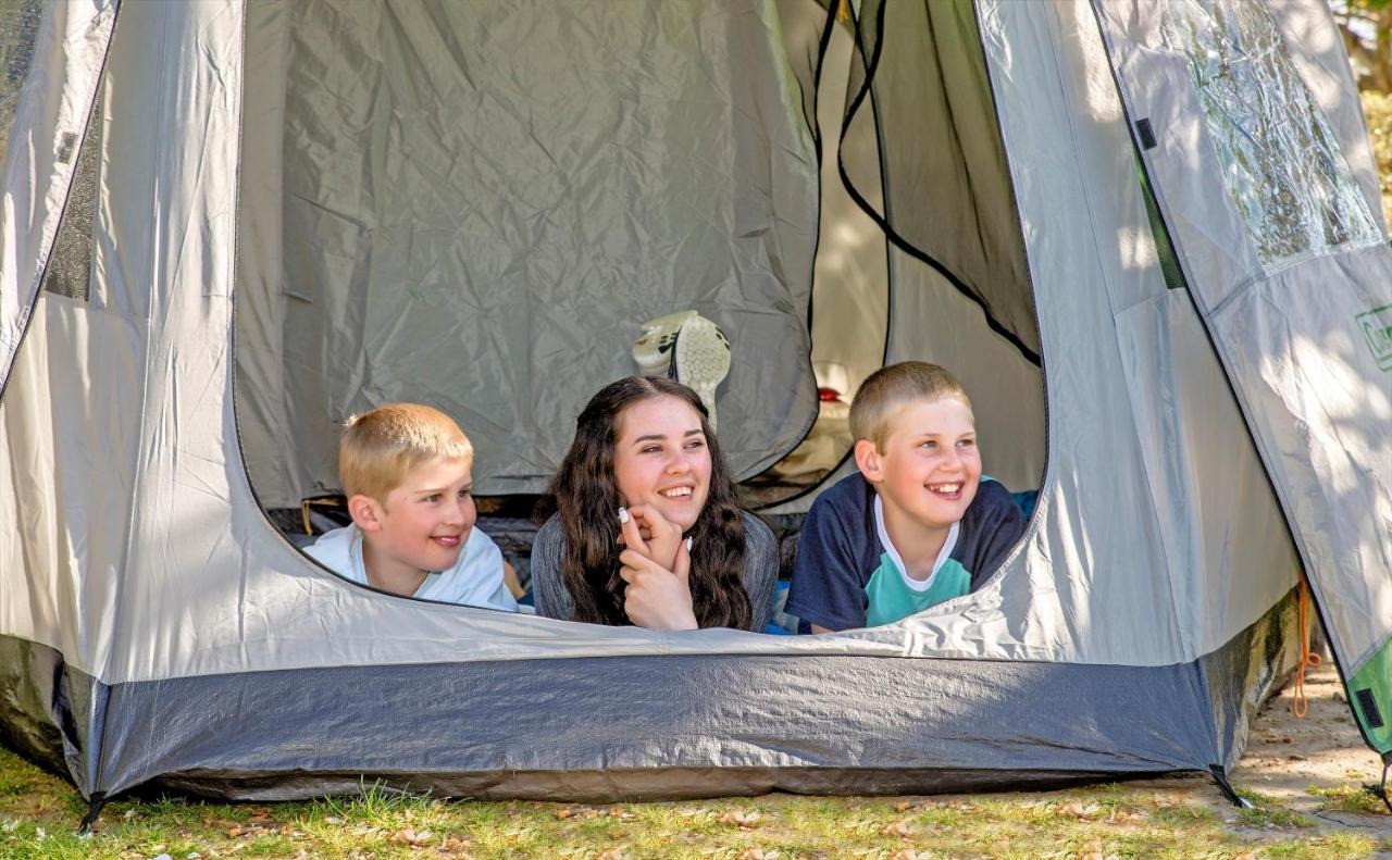 陶波德布雷思汽车旅馆酒店 外观 照片 The photo shows three children inside a tent, looking out from an opening. Two boys are on the left, one with short blonde hair and the other with light brown hair, while the girl in the middle has long dark hair. They all appear to be happy and enga