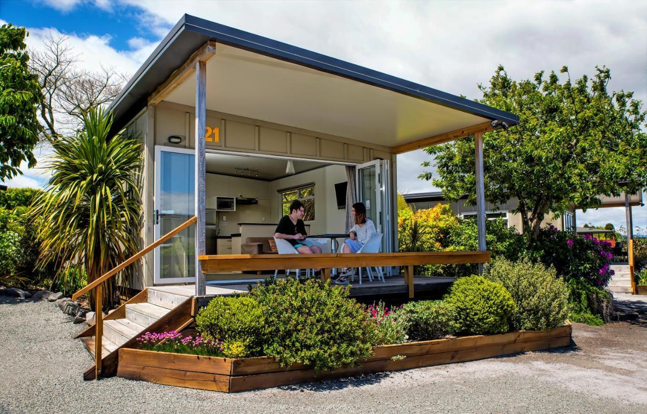 陶波德布雷思汽车旅馆酒店 外观 照片 The photo depicts a modern small house or cabin, featuring a covered porch with a wooden railing. Two people are seated at a table on the porch, engaging in conversation. The exterior of the house is designed with large windows, allowing ample natura